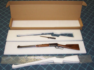 A rifle on foam packaging on a checkered surface